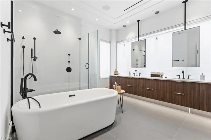 Bathroom featuring double vanity, a freestanding bath, walk in shower, and light tile patterned flooring