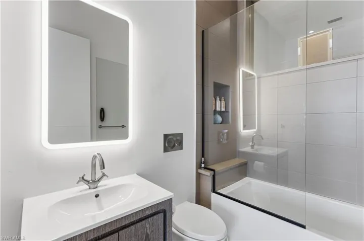 Bathroom with vanity and combined bath / shower with glass door