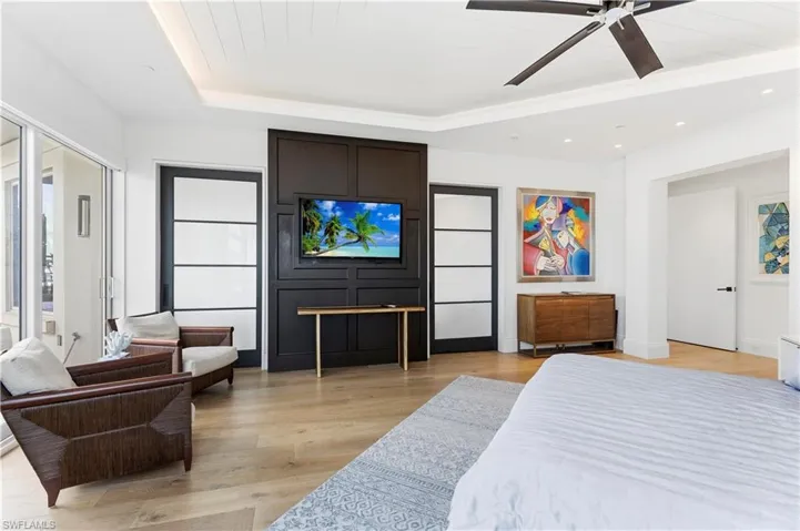 Bedroom with light wood finished floors, a ceiling fan, recessed lighting, and a tray ceiling