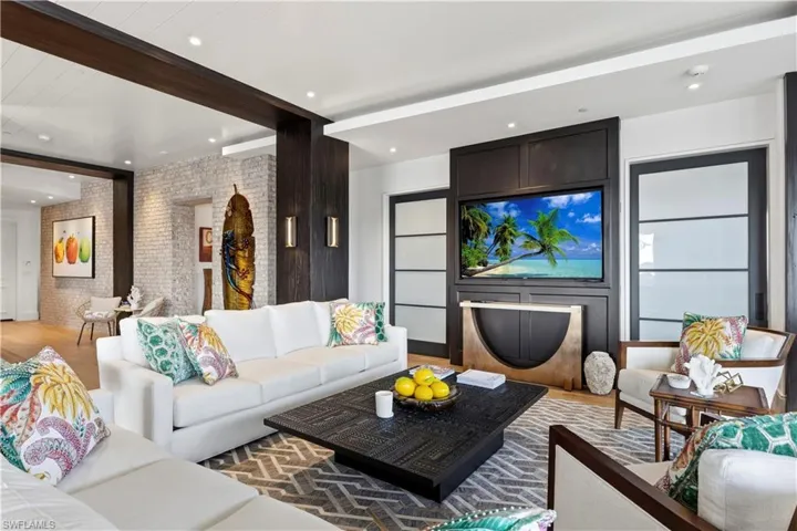 Living area with brick wall, light wood-style flooring, recessed lighting, and beam ceiling