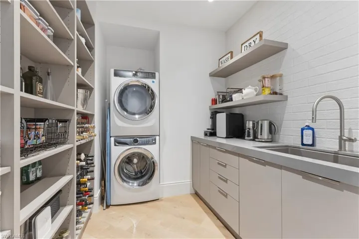 Laundry room featuring stacked washer and dryer and light wood-style flooring