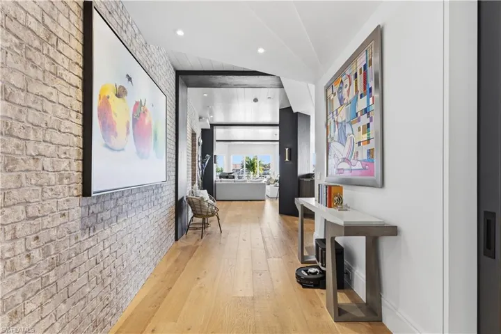 Hall featuring brick wall, light wood finished floors, recessed lighting, and an accent wall