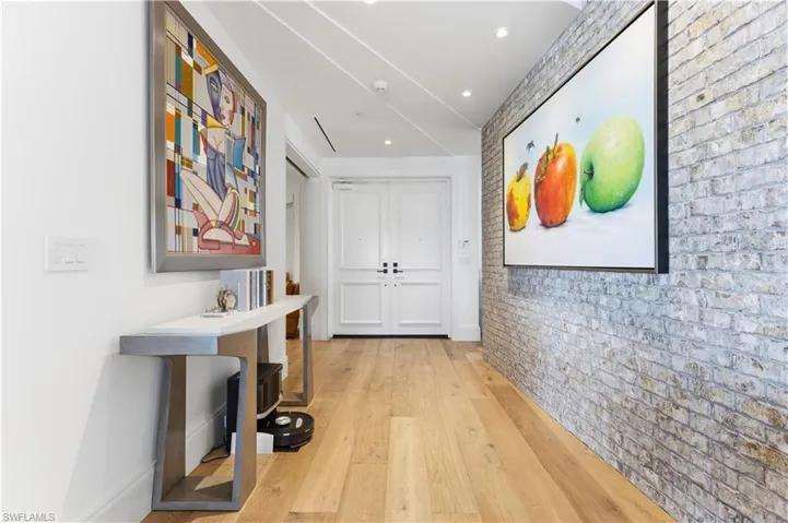 Hallway featuring brick wall and light wood-type flooring