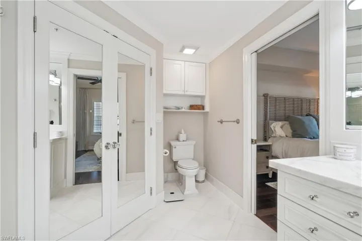 Bathroom with french doors, toilet, vanity, tile patterned floors, and ornamental molding