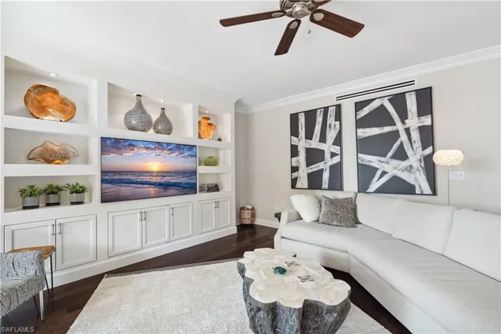 Living room featuring built in features, ceiling fan, dark hardwood / wood-style flooring, and ornamental molding
