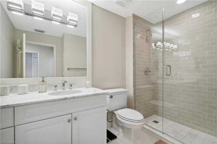 Bathroom featuring tile patterned floors, a shower with door, toilet, and vanity