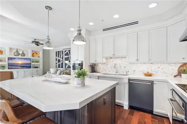 Kitchen with stainless steel appliances, sink, a kitchen island, decorative backsplash, and dark hardwood / wood-style flooring