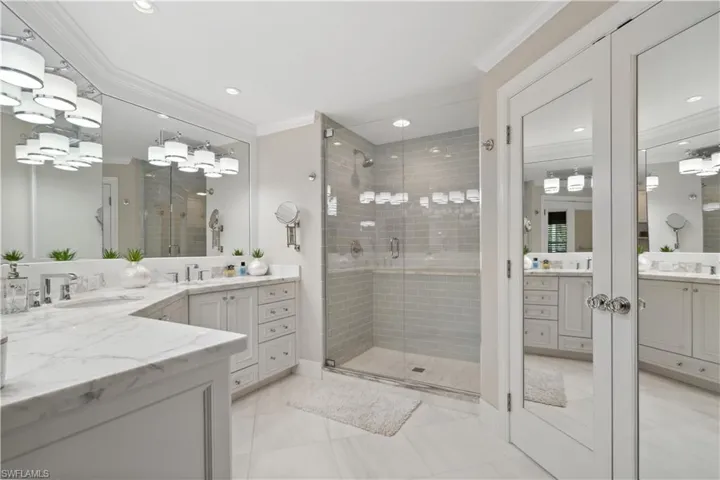 Bathroom featuring crown molding, tile patterned flooring, an enclosed shower, and dual bowl vanity