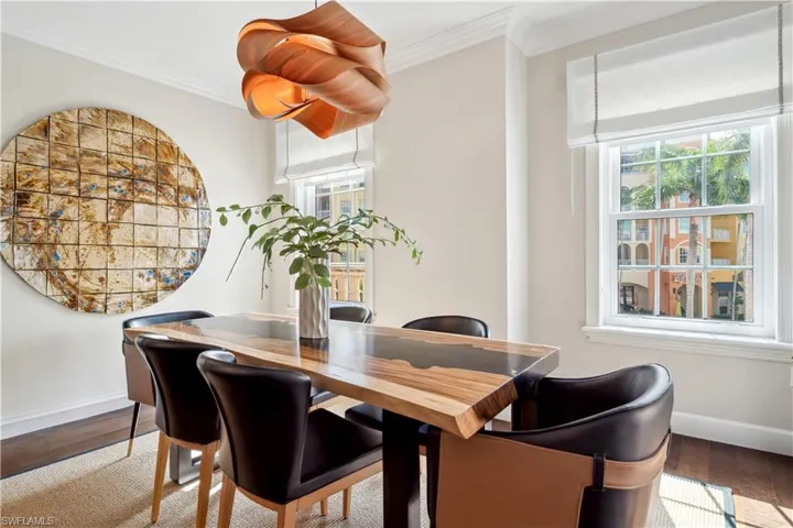 Dining space with wood-type flooring and crown molding