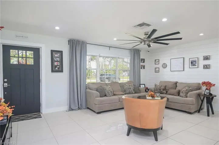Living room featuring wooden walls, light tile patterned flooring, and ceiling fan