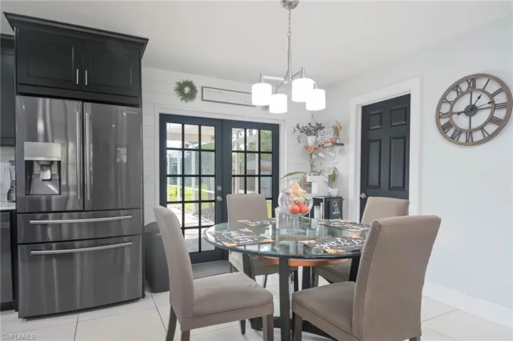 Dining space with french doors, an inviting chandelier, and light tile patterned floors