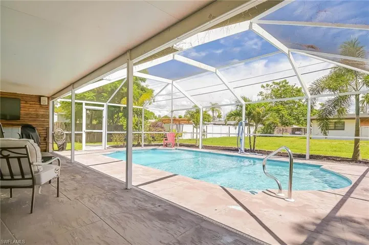View of swimming pool with a patio, glass enclosure, and a lawn