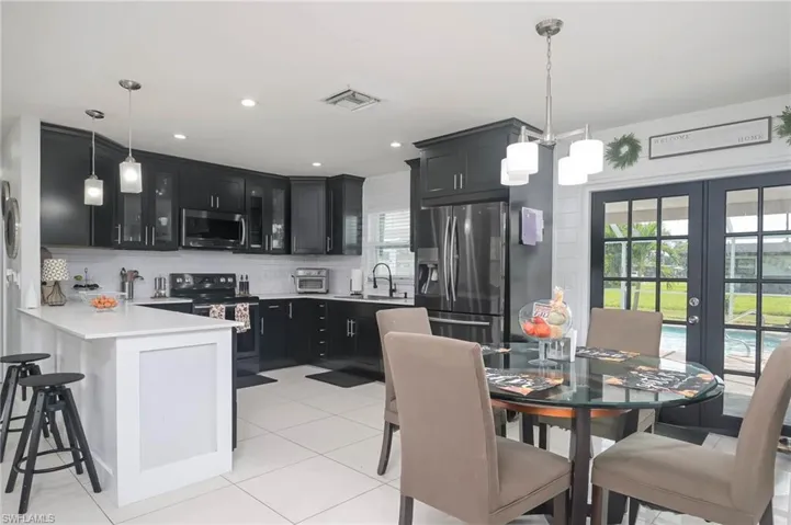 Kitchen with kitchen peninsula, tasteful backsplash, appliances with stainless steel finishes, pendant lighting, and french doors