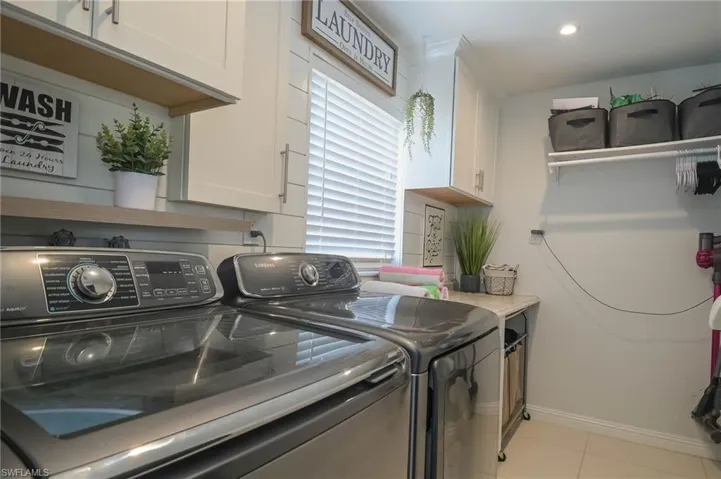 Clothes washing area featuring independent washer and dryer, a healthy amount of sunlight, cabinets, and light tile patterned floors