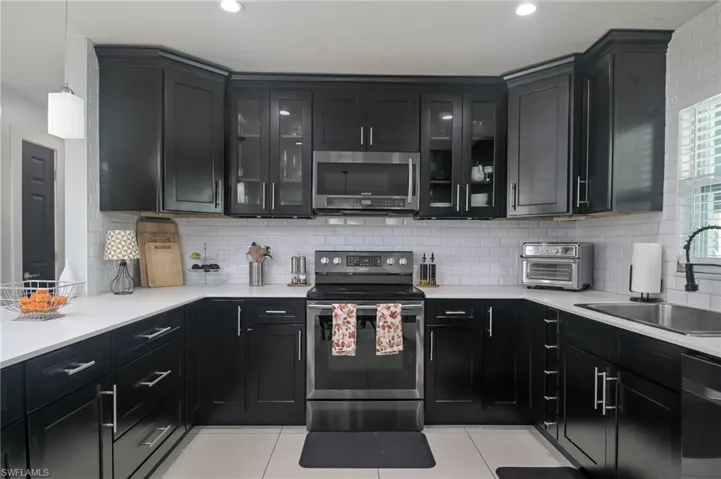 Kitchen featuring sink, stainless steel appliances, backsplash, and light tile patterned floors
