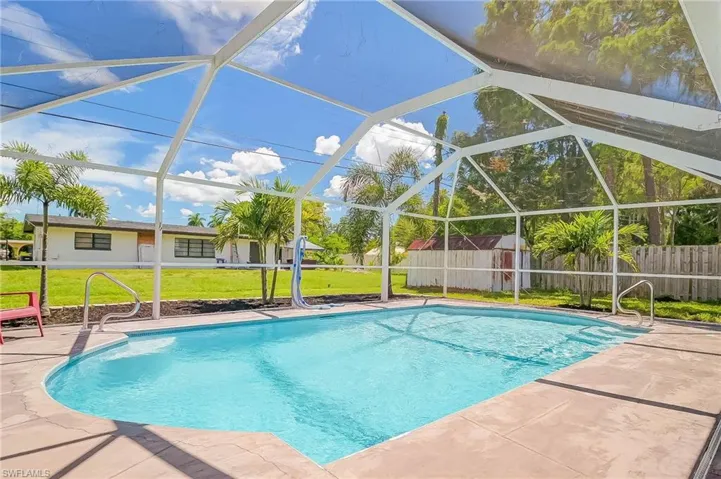 View of swimming pool featuring a patio, a storage unit, a lawn, and a lanai