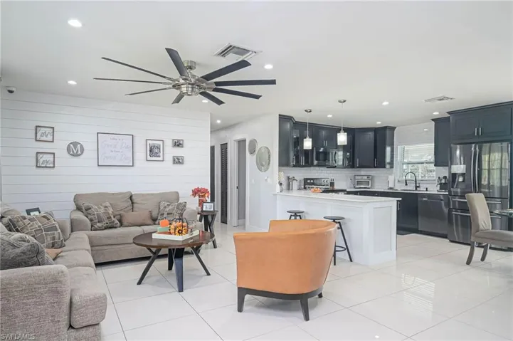 Tiled living room featuring ceiling fan, wood walls, and sink