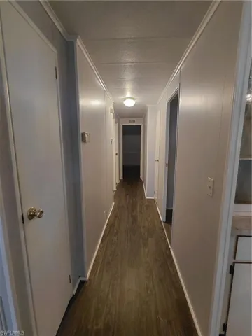 Hall with dark wood-style flooring, ornamental molding, and a textured ceiling