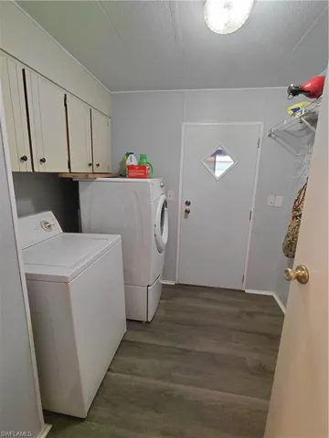 Washroom featuring cabinet space, dark wood-type flooring, washer and dryer, and a textured ceiling
