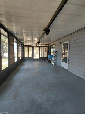 Unfurnished sunroom with finished concrete flooring and ceiling fan