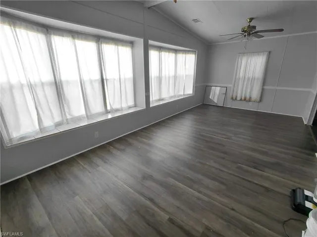 Unfurnished room with dark wood finished floors and ceiling fan