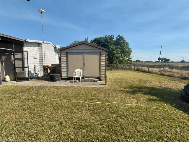 Fenced backyard featuring a storage unit, a patio area, and a sunroom