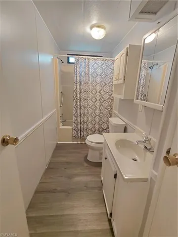 Bathroom featuring vanity, shower / bath combo, dark wood-style flooring, and a textured ceiling
