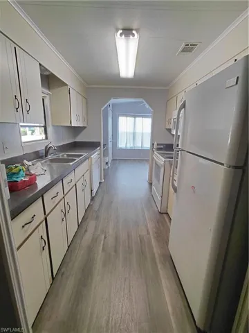Kitchen with refrigerator, dark countertops, crown molding, plenty of natural light, and light wood-type flooring