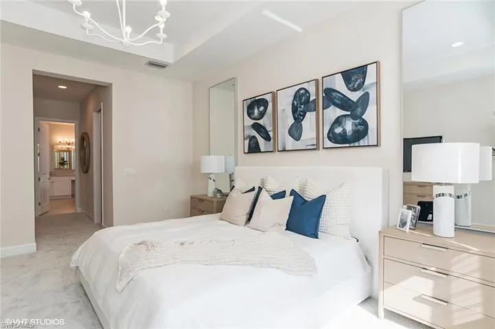 Bedroom featuring a chandelier, light carpet, and ensuite bath