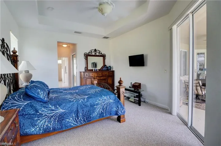 Bedroom with access to outside, light carpet, a ceiling fan, and a raised ceiling