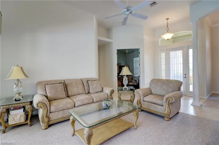 Living room featuring ornate columns, a ceiling fan, and tile patterned flooring