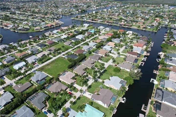 Aerial view of property and surrounding area featuring a nearby body of water and nearby suburban area