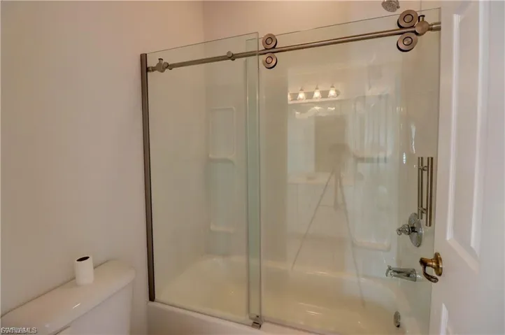 Full bathroom with toilet and bath / shower combo with glass door