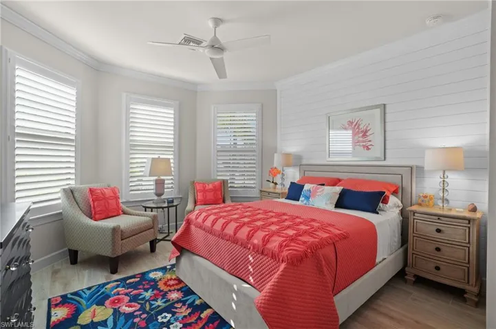 En suite guest room has bow windows with plantation shutters and a shiplap feature wall