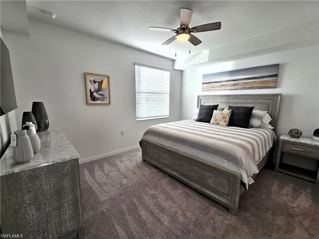 Bedroom featuring baseboards, ceiling fan, and dark carpet
