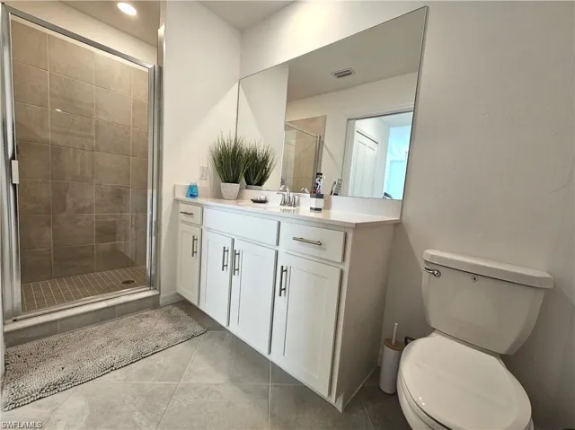 Full bath featuring vanity, toilet, a shower stall, tile patterned floors, and visible vents