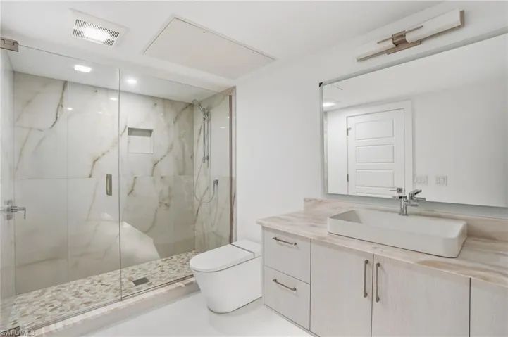 Bathroom featuring vanity and a marble finish shower