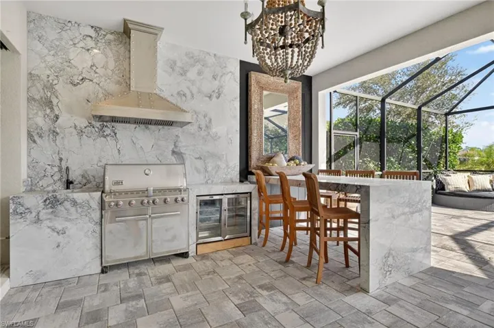 View of patio with exterior kitchen, glass enclosure, a sunroom, and beverage cooler