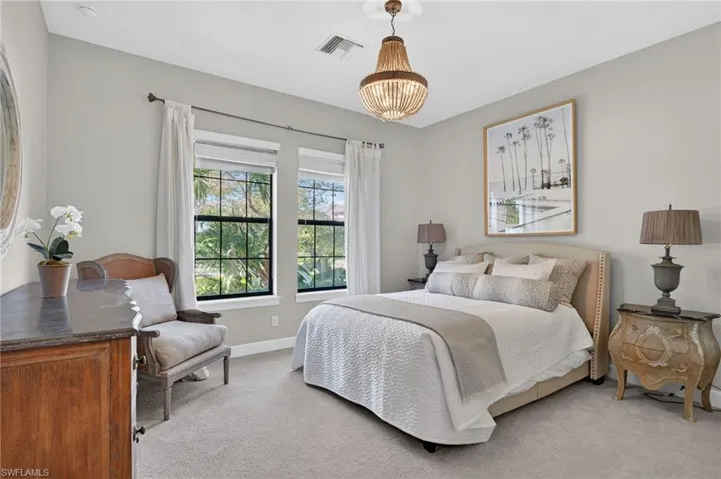 Bedroom with light colored carpet and suspended lighting