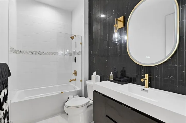 Full bath featuring shower / washtub combination, vanity, and tile walls
