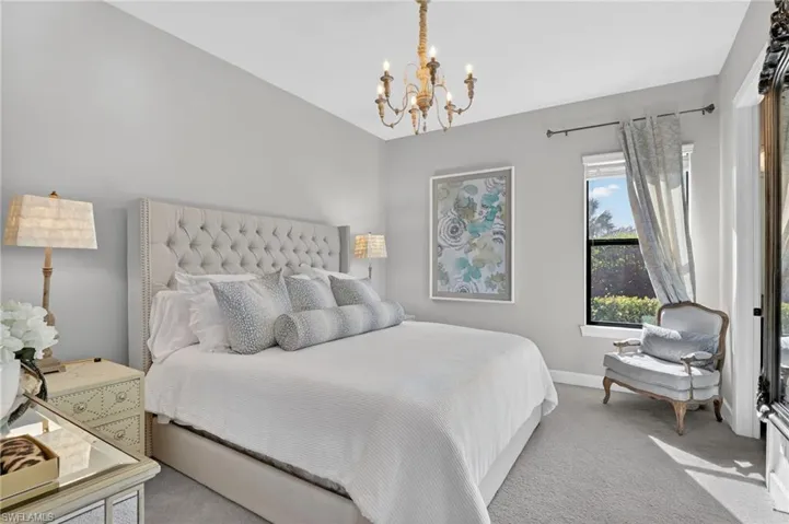 Carpeted bedroom featuring a chandelier and baseboards