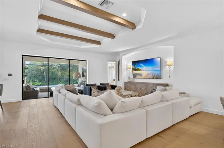 Living area with crown molding, light wood-style flooring, beam ceiling, and recessed lighting
