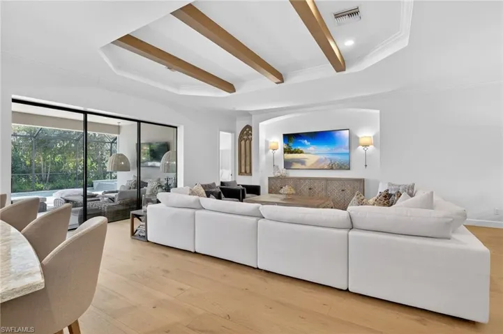 Living room with ornamental molding, light wood-style floors, beam ceiling, and recessed lighting