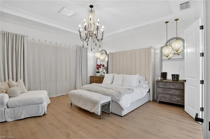 Bedroom featuring a chandelier, crown molding, and wood finished floors