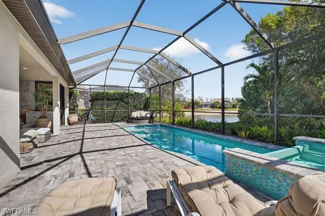 Swimming pool featuring glass enclosure, a sunroom, a water view, a patio, and an outdoor hangout area