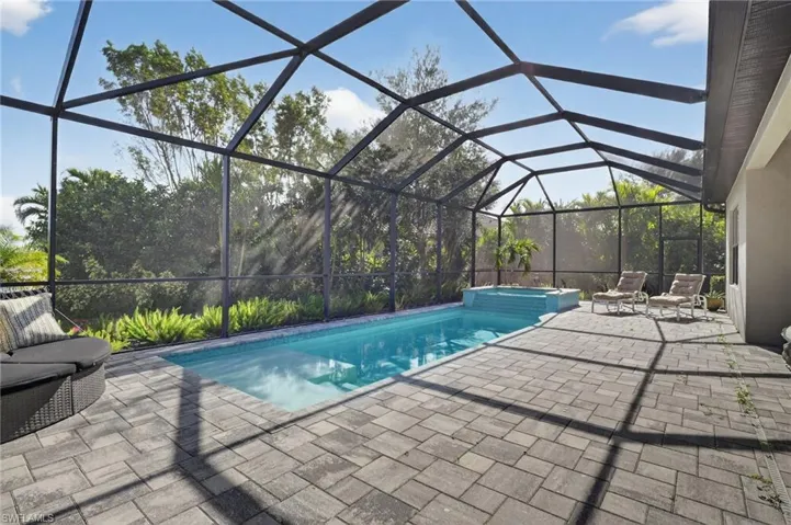 Integrated pool / spa with a sunroom, glass enclosure, and a patio area