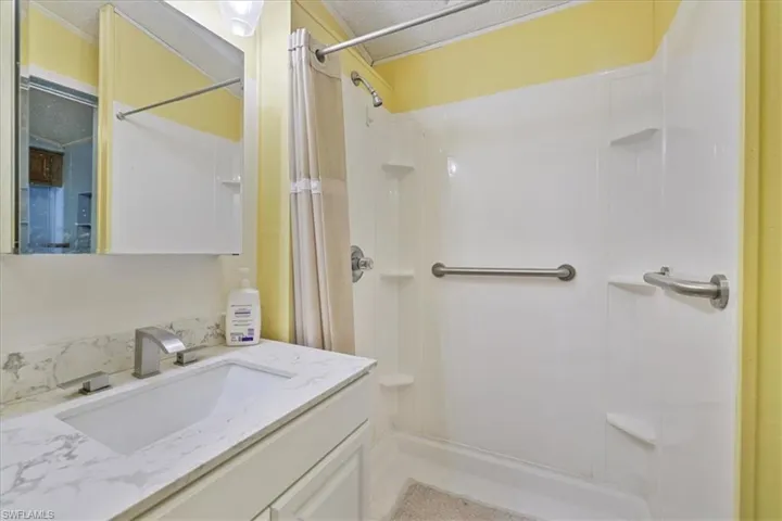 Bathroom with vanity, a stall shower, and a textured ceiling