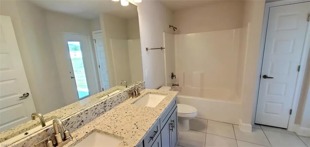 Full bathroom with tile patterned flooring, vanity, toilet, and  shower combination