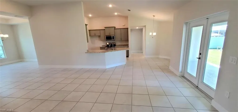 Kitchen featuring light stone countertops, light tile patterned floors, plenty of natural light, and sink