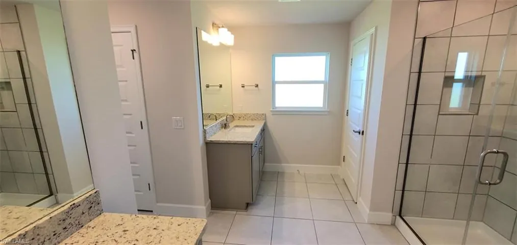 Primary Bathroom with vanity, tile patterned floors, and a shower with door